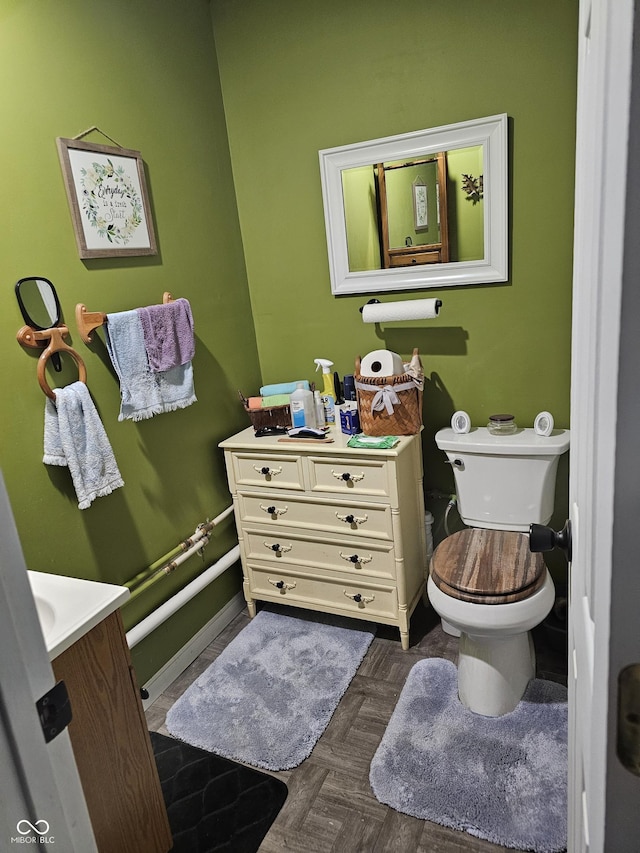 bathroom with toilet, vanity, and parquet flooring