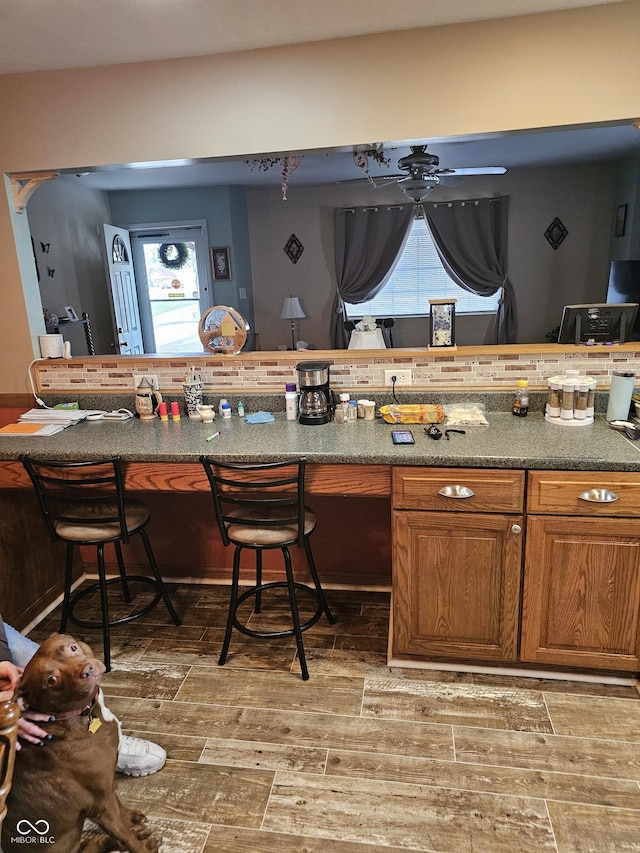 kitchen with hardwood / wood-style flooring, ceiling fan, and a breakfast bar area