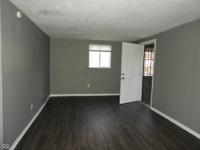 spare room with a textured ceiling and dark hardwood / wood-style flooring