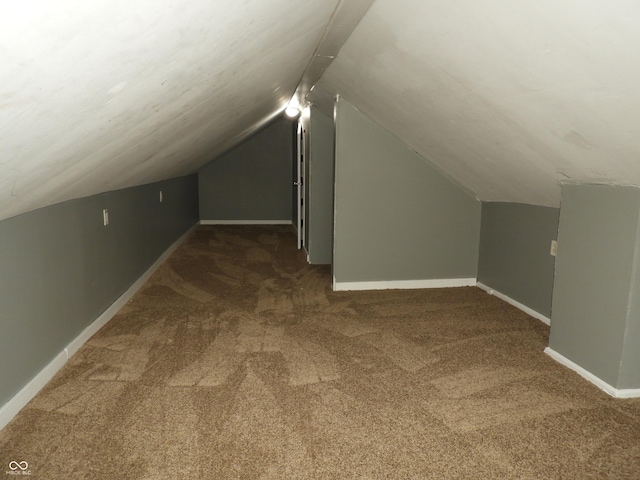 bonus room with vaulted ceiling and dark colored carpet