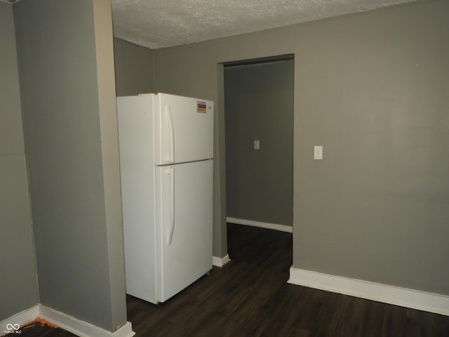 kitchen with a textured ceiling, white fridge, and dark wood-type flooring