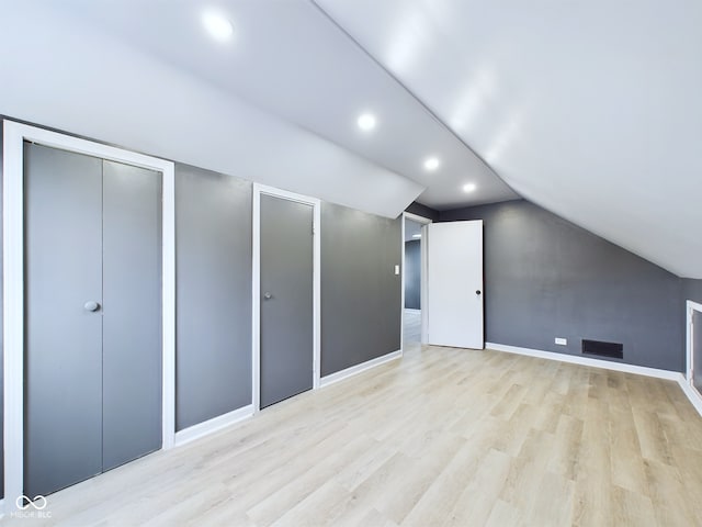 additional living space featuring lofted ceiling and light wood-type flooring