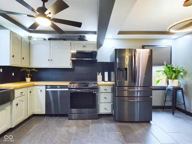 kitchen featuring tasteful backsplash, stainless steel appliances, a raised ceiling, ceiling fan, and white cabinets