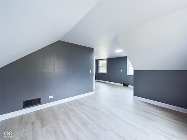 additional living space with light hardwood / wood-style flooring and lofted ceiling