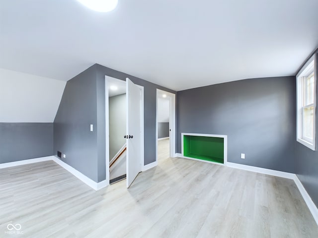 additional living space with light hardwood / wood-style flooring and lofted ceiling