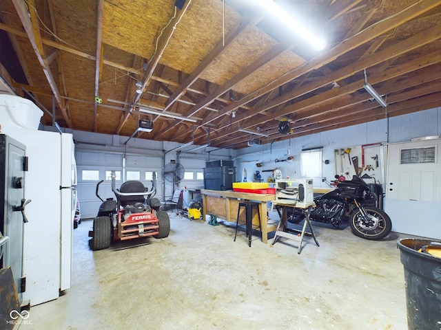 garage with a workshop area, white fridge, and a garage door opener