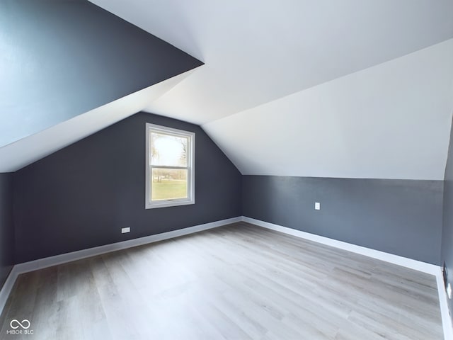 additional living space with light hardwood / wood-style floors and vaulted ceiling