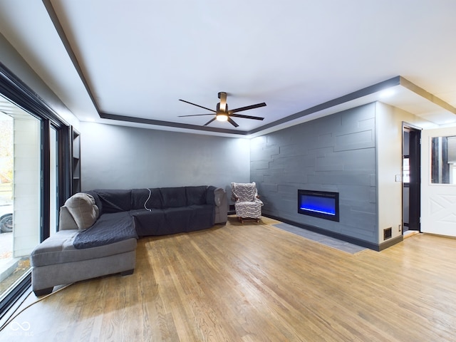 living room with hardwood / wood-style floors, ceiling fan, and a large fireplace