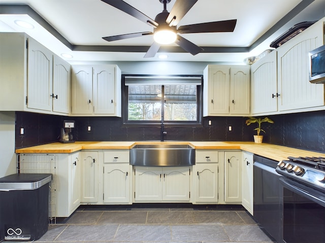 kitchen featuring backsplash, ceiling fan, black stove, and sink