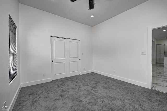 unfurnished bedroom with ceiling fan, dark carpet, and a closet