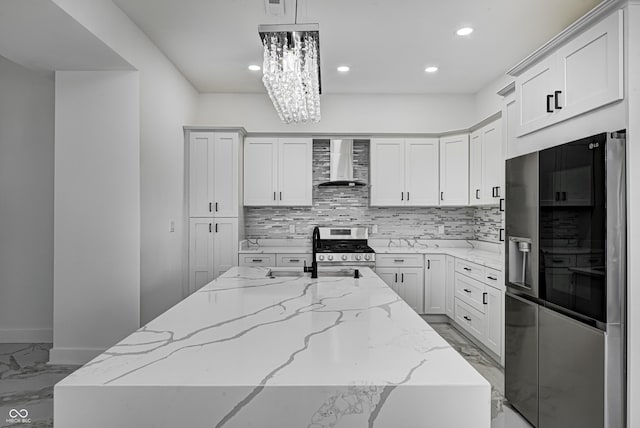 kitchen with appliances with stainless steel finishes, backsplash, light stone counters, wall chimney exhaust hood, and hanging light fixtures