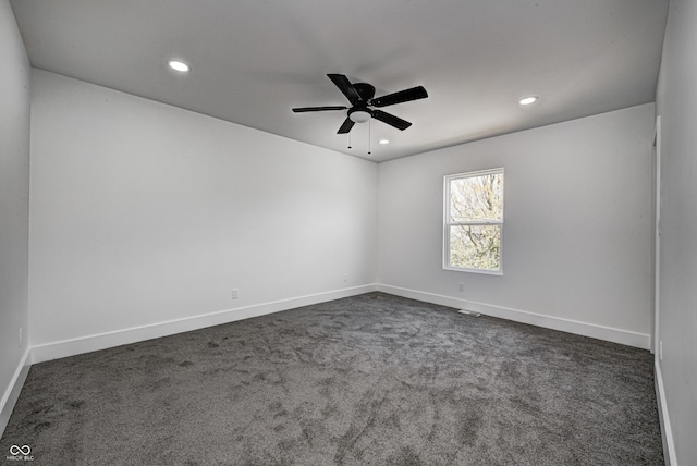 spare room featuring ceiling fan and dark carpet