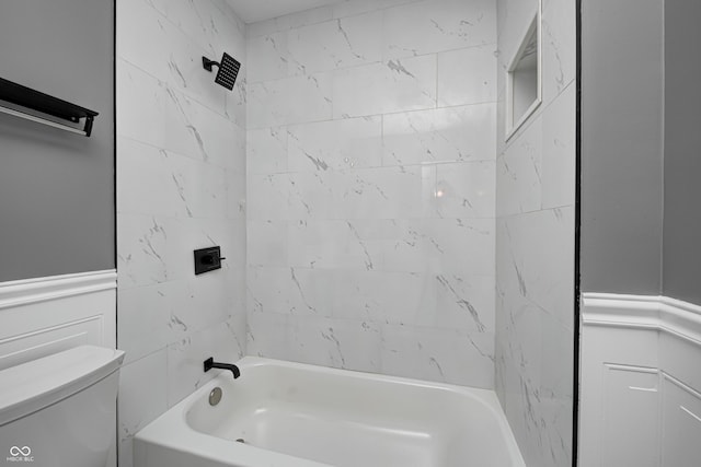 bathroom featuring toilet and tiled shower / bath