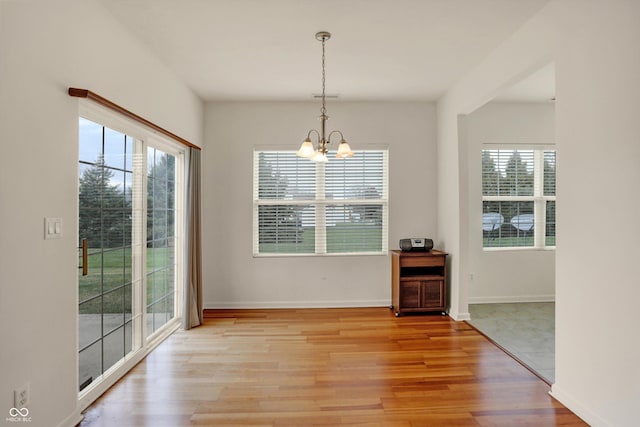 unfurnished dining area with light hardwood / wood-style floors and an inviting chandelier