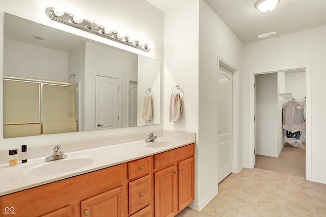 bathroom with tile patterned flooring, vanity, and walk in shower