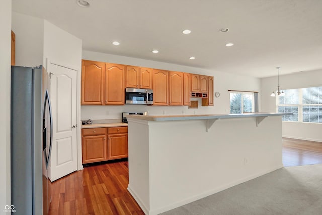 kitchen featuring stainless steel appliances, dark wood-type flooring, pendant lighting, a notable chandelier, and a kitchen island