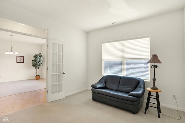 sitting room with a notable chandelier, carpet floors, and french doors