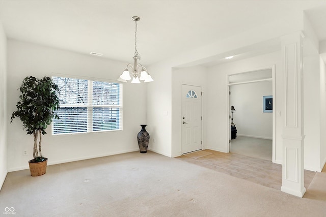 carpeted foyer with an inviting chandelier