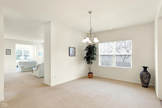 unfurnished room featuring light carpet and a chandelier