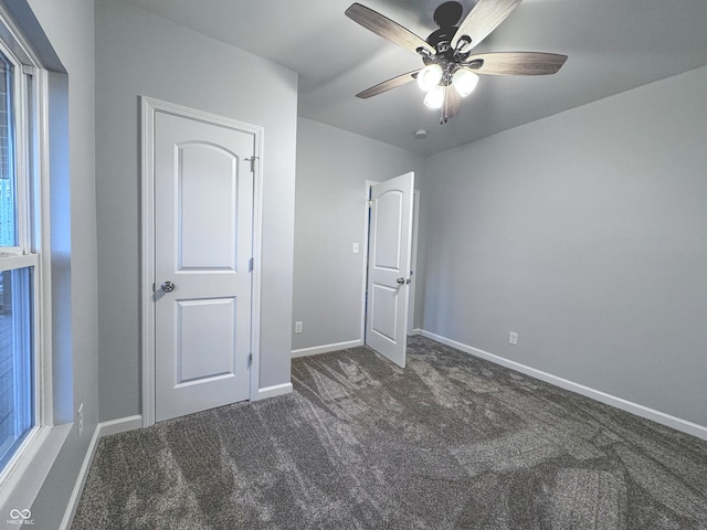 unfurnished bedroom with ceiling fan and dark colored carpet