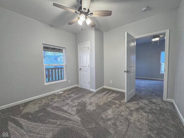 unfurnished bedroom with ceiling fan and dark carpet