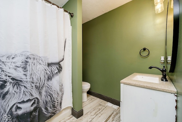 bathroom with hardwood / wood-style floors, vanity, a shower with shower curtain, toilet, and a textured ceiling