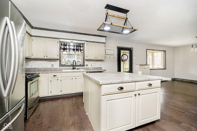 kitchen with appliances with stainless steel finishes, sink, pendant lighting, dark hardwood / wood-style floors, and a kitchen island