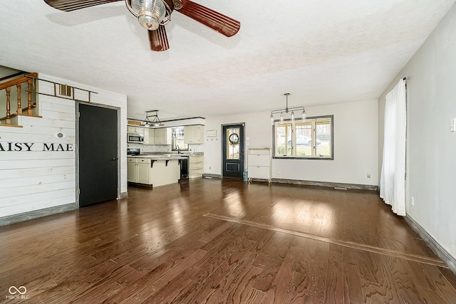 unfurnished living room with ceiling fan, dark hardwood / wood-style flooring, a textured ceiling, and sink