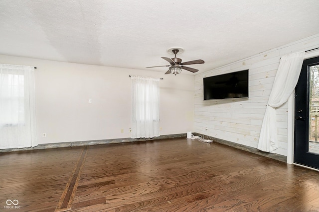 spare room with a textured ceiling, dark hardwood / wood-style flooring, and plenty of natural light