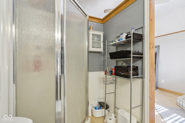 bathroom with hardwood / wood-style floors, a shower with door, and toilet