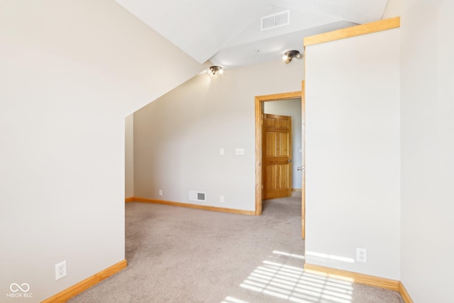 additional living space featuring light carpet and vaulted ceiling