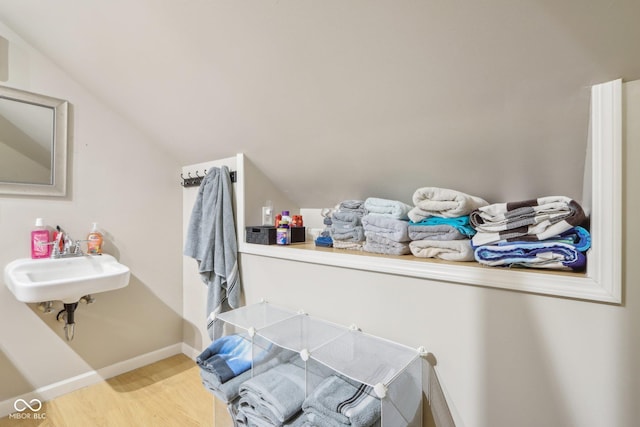 spacious closet with lofted ceiling, sink, and light hardwood / wood-style flooring