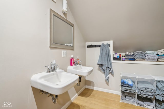 bathroom featuring hardwood / wood-style floors, vaulted ceiling, and sink