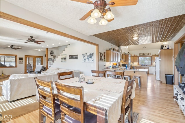 dining space featuring sink, a textured ceiling, and light hardwood / wood-style floors