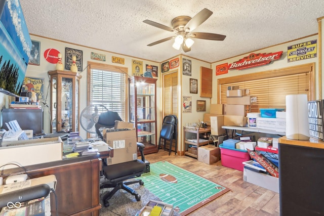 office space with a textured ceiling, ornamental molding, light hardwood / wood-style floors, and ceiling fan