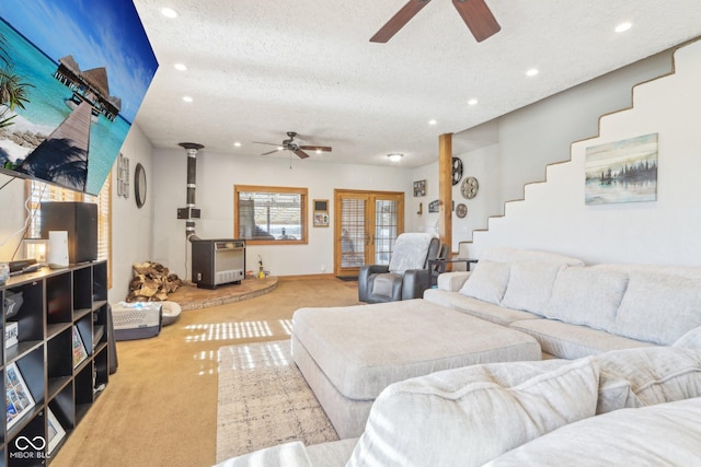 carpeted living room with ceiling fan, a wood stove, a textured ceiling, and french doors