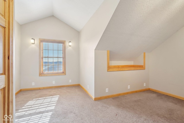 bonus room with light colored carpet and lofted ceiling