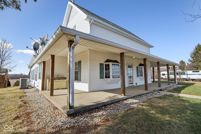 view of side of property featuring a patio, central AC, and a lawn