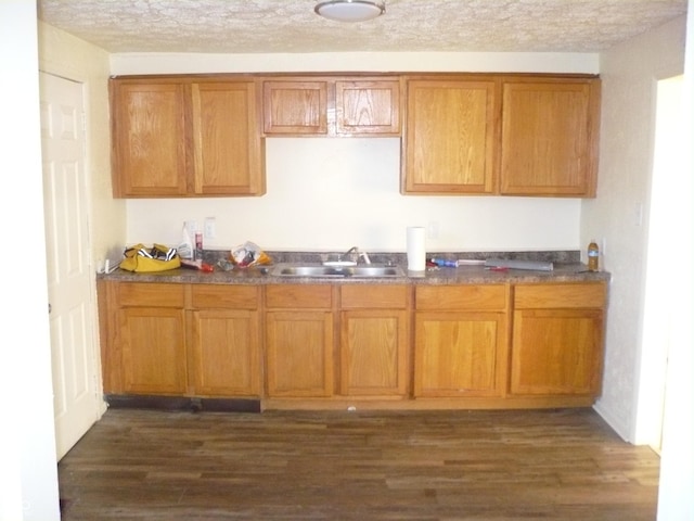 kitchen with a textured ceiling, sink, and dark wood-type flooring