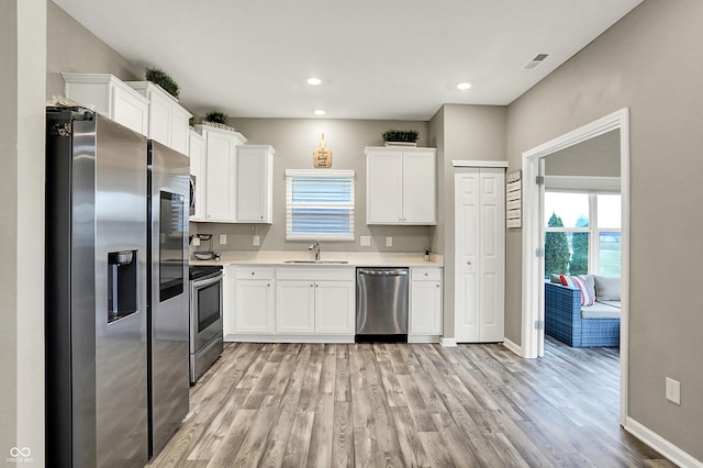 kitchen with sink, light hardwood / wood-style floors, white cabinets, and appliances with stainless steel finishes