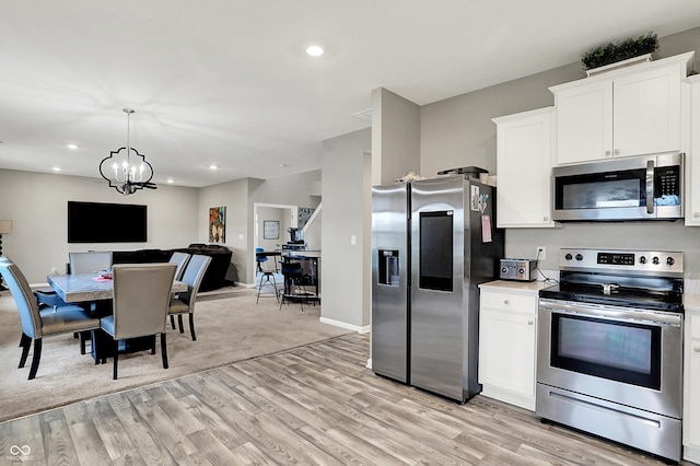 kitchen featuring stainless steel appliances, decorative light fixtures, light hardwood / wood-style floors, and white cabinets