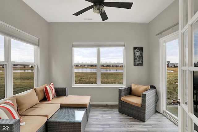 sunroom featuring ceiling fan and a water view