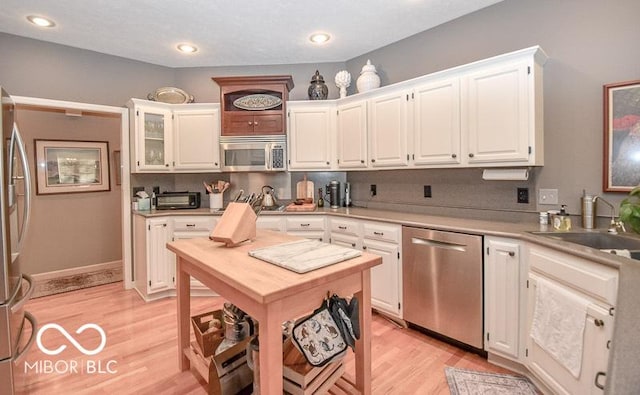 kitchen featuring white cabinets, light hardwood / wood-style floors, sink, and appliances with stainless steel finishes