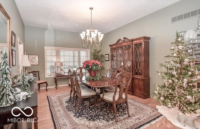 dining room featuring a textured ceiling, an inviting chandelier, and light hardwood / wood-style flooring