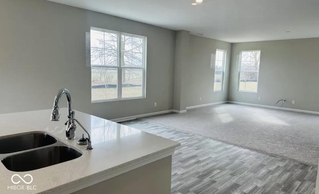 kitchen featuring light stone counters, light colored carpet, sink, and a wealth of natural light