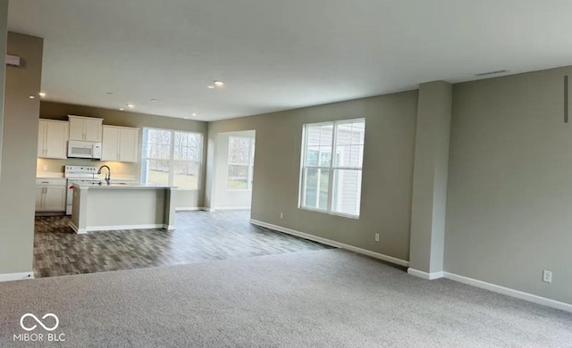 unfurnished living room featuring carpet flooring and a wealth of natural light