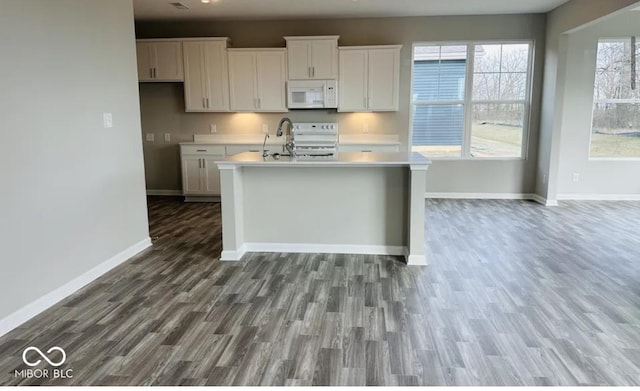 kitchen with sink, white appliances, a center island with sink, white cabinets, and hardwood / wood-style flooring