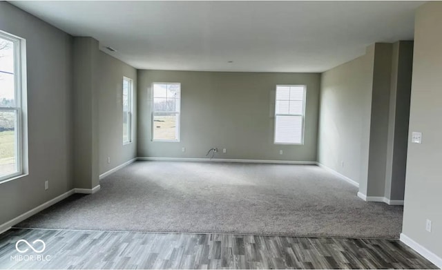 empty room featuring dark wood-type flooring and a healthy amount of sunlight