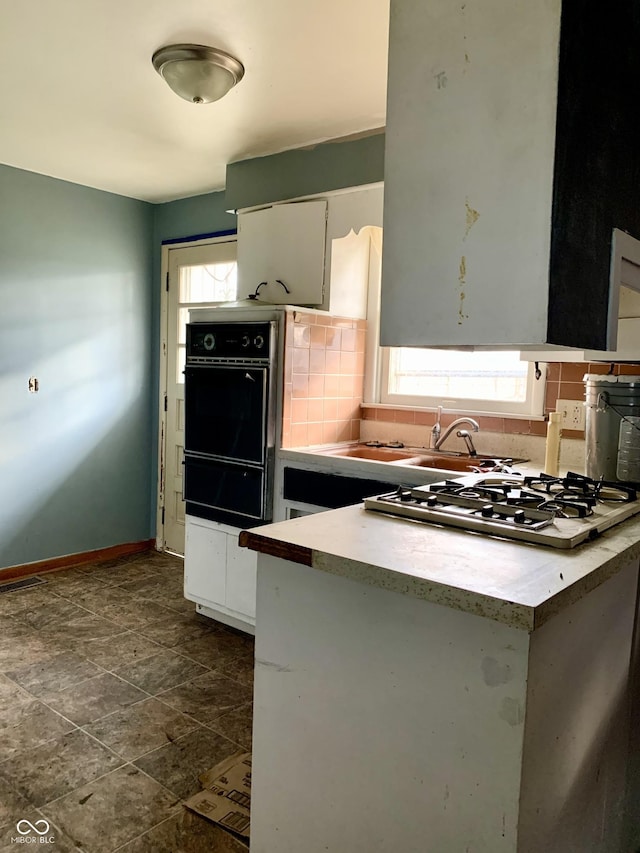 kitchen with white cabinets, backsplash, oven, and white gas stovetop