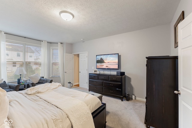 bedroom featuring light colored carpet and a textured ceiling